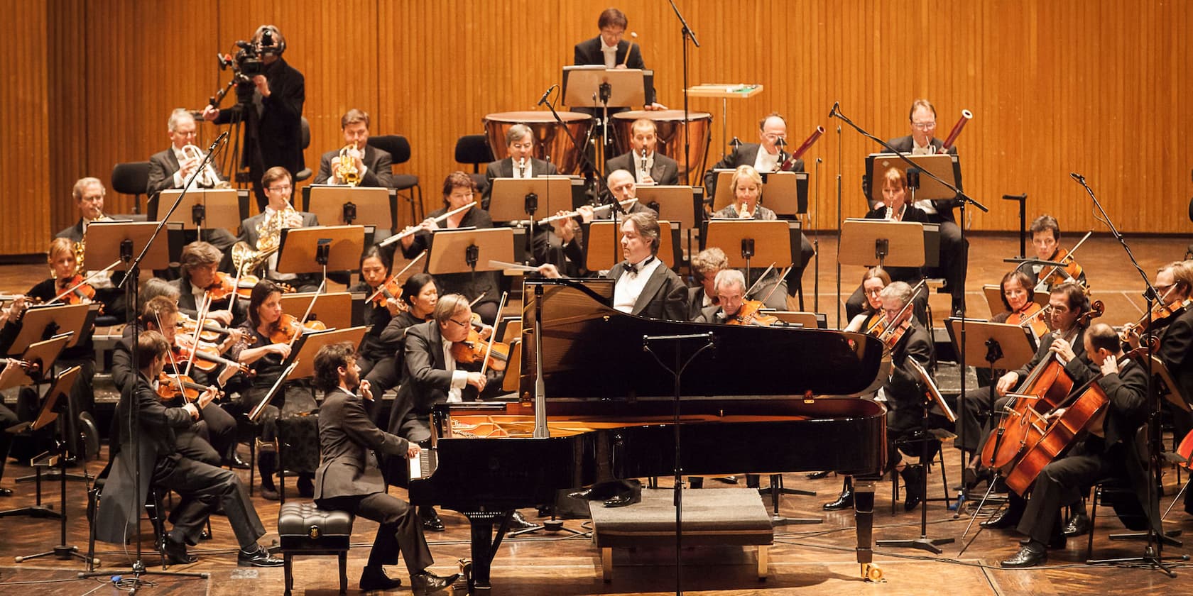 An orchestra performing a concert, with a pianist in the foreground.