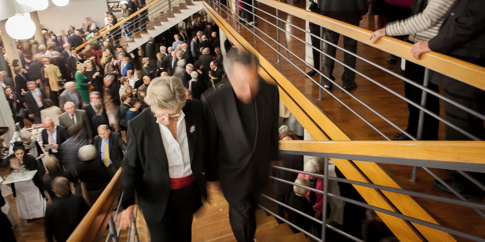 Several people at an event in a large room with a staircase.