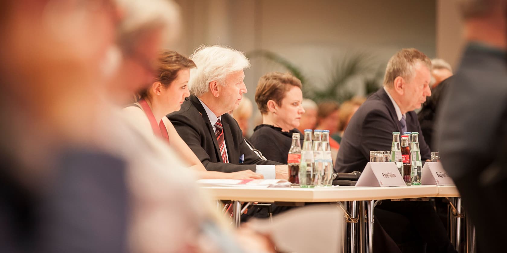 Menschen sitzen an einem Konferenztisch während einer Veranstaltung.