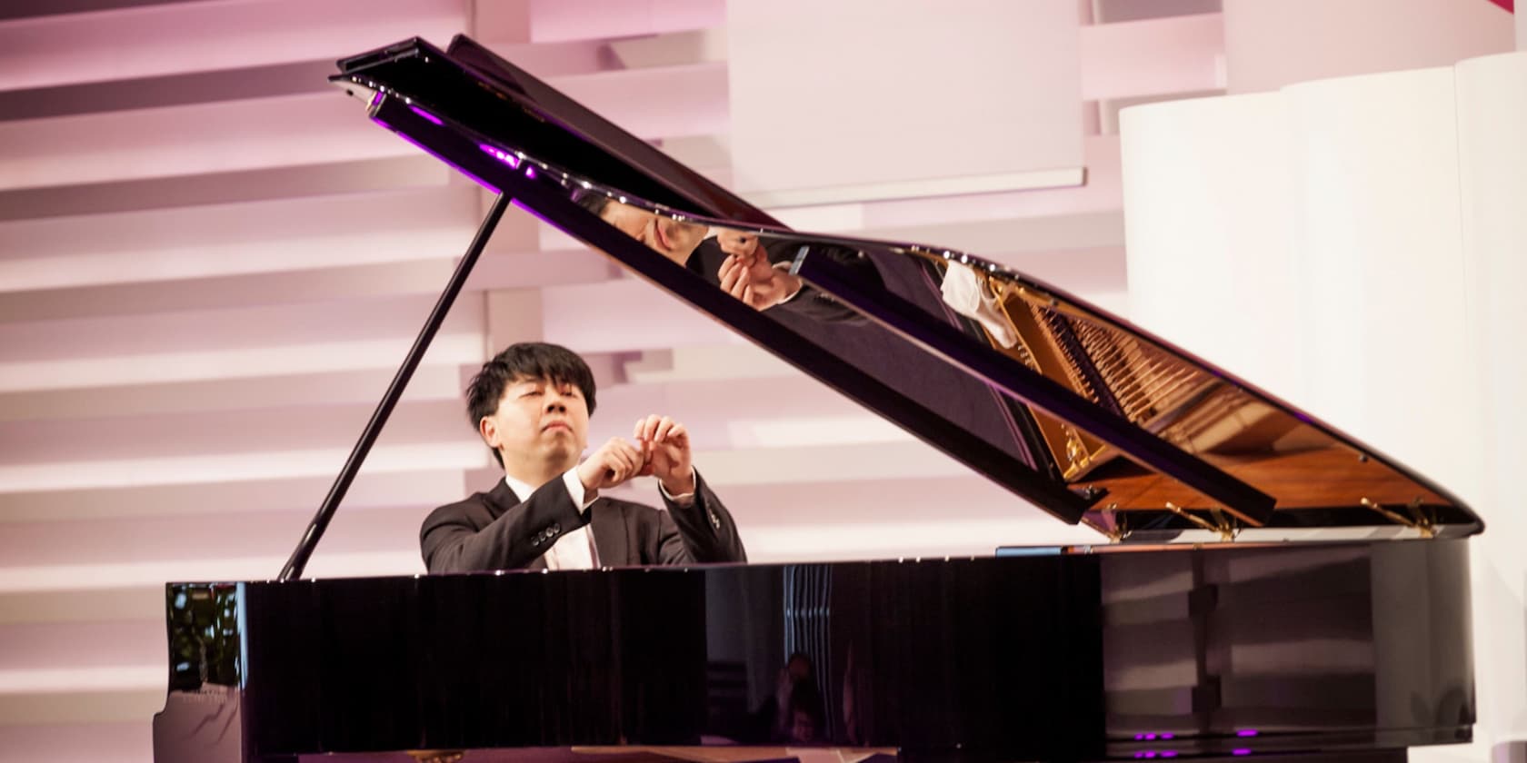 A pianist playing a grand piano at a concert.