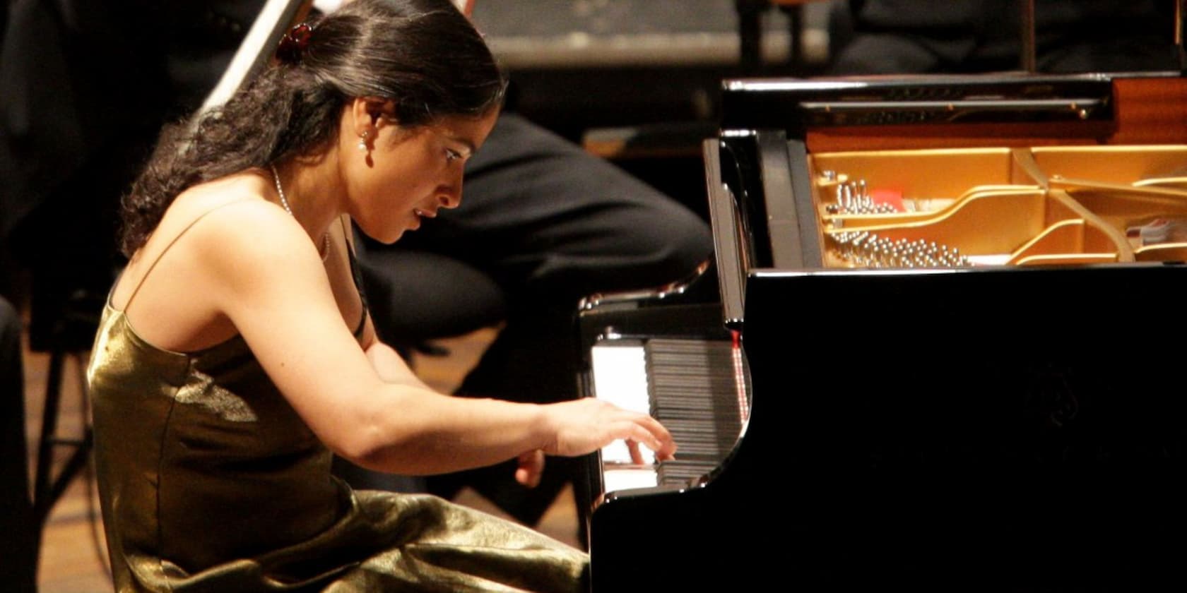 A woman plays the piano with focus.