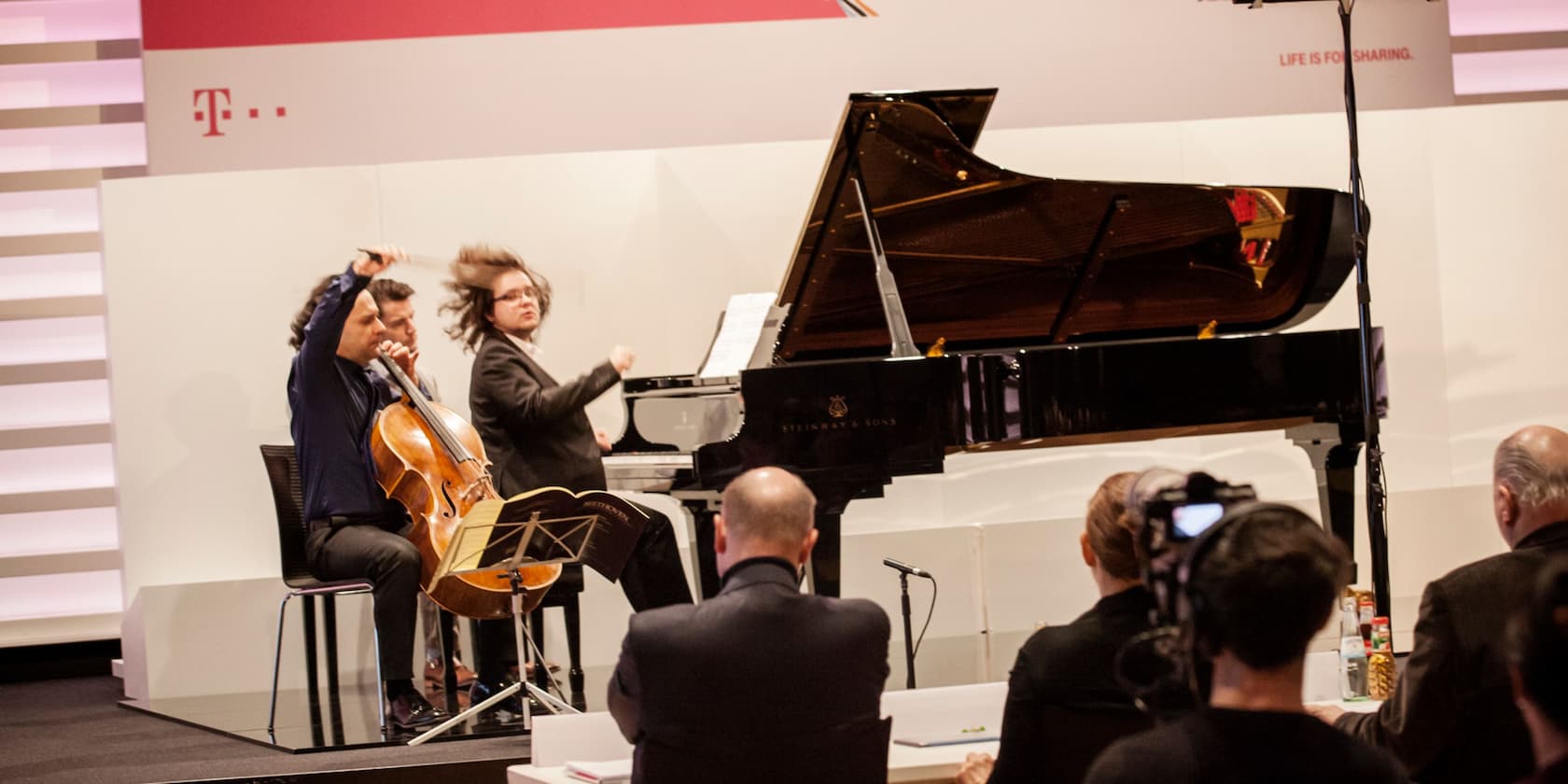 Ein Cellist und ein Pianist performen vor einem Publikum bei einer Veranstaltung.