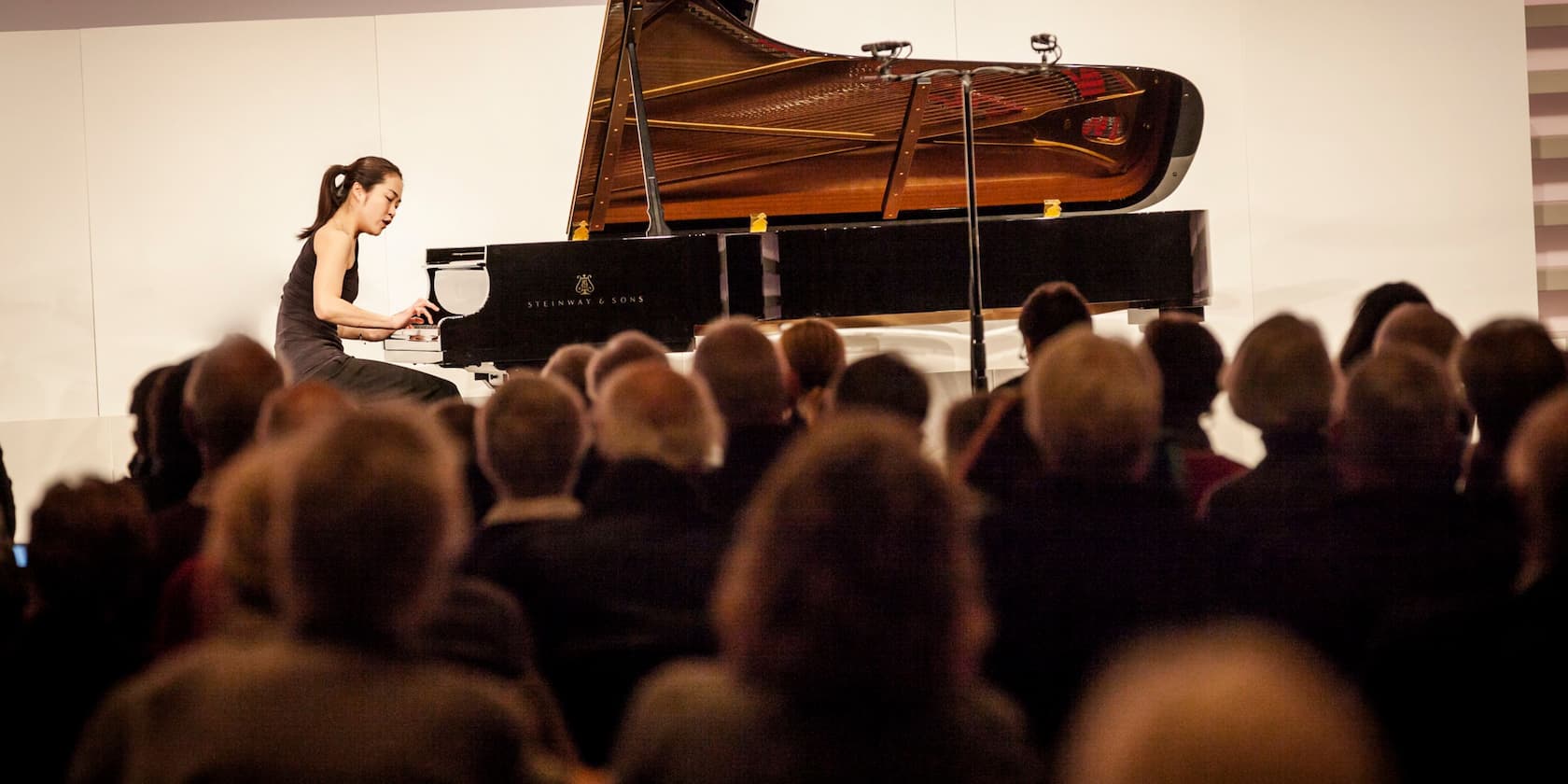 A woman playing piano on stage in front of an audience.