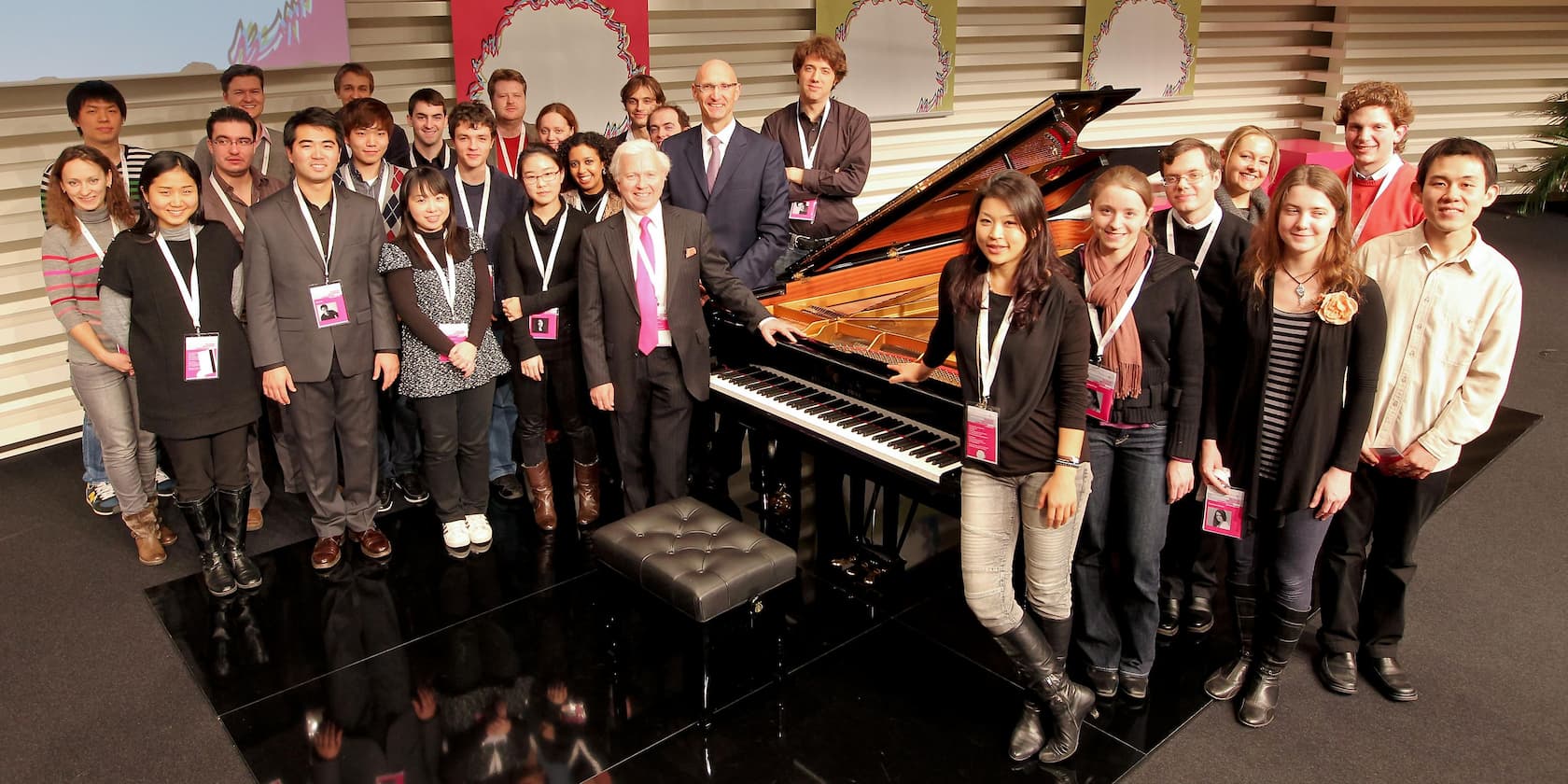 Group of people posing around a piano at an event.