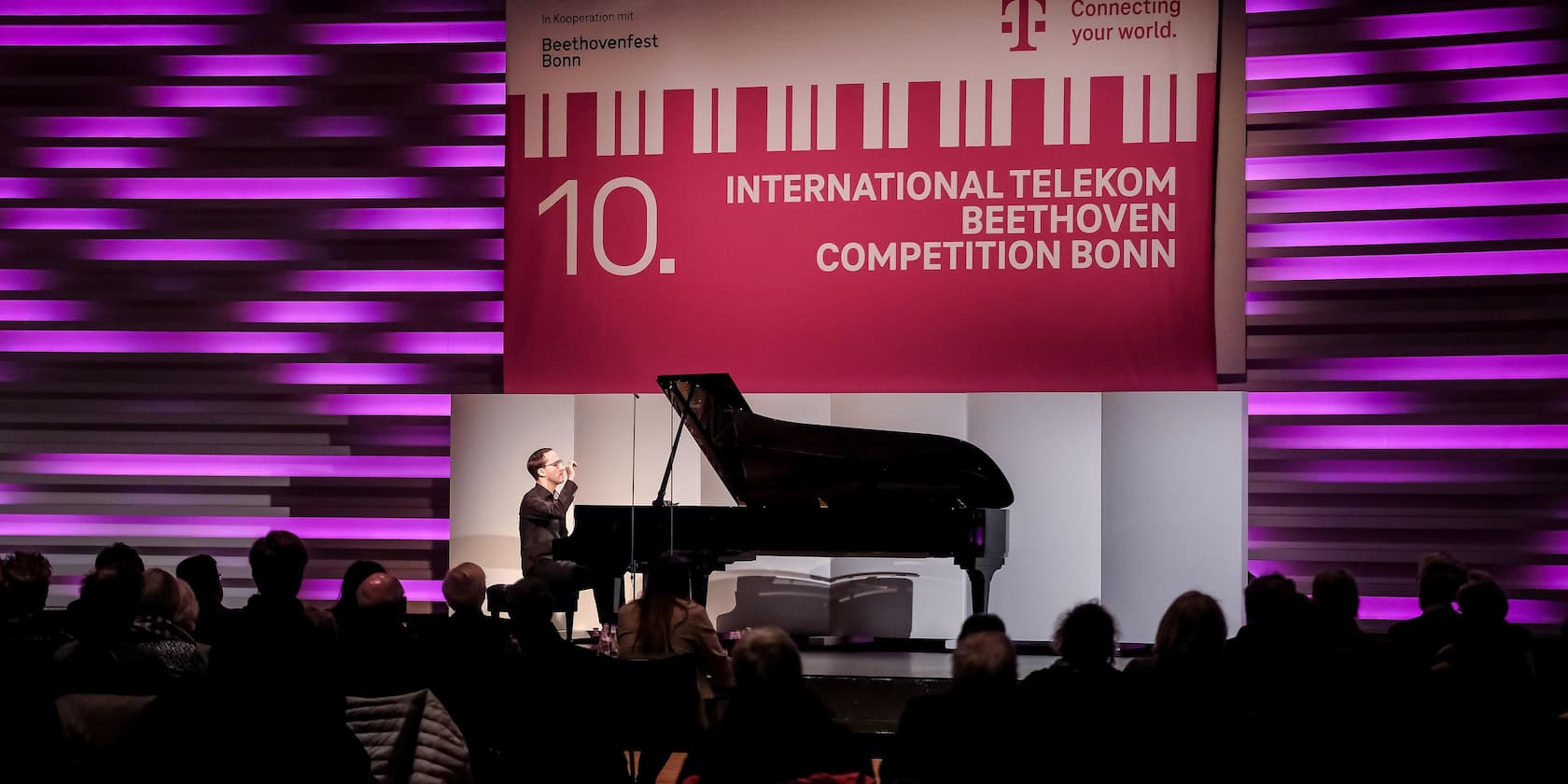 Ein Pianist tritt bei der 10. International Telekom Beethoven Competition in Bonn auf. Im Hintergrund ist ein großes Banner mit dem Wettbewerbsnamen zu sehen.