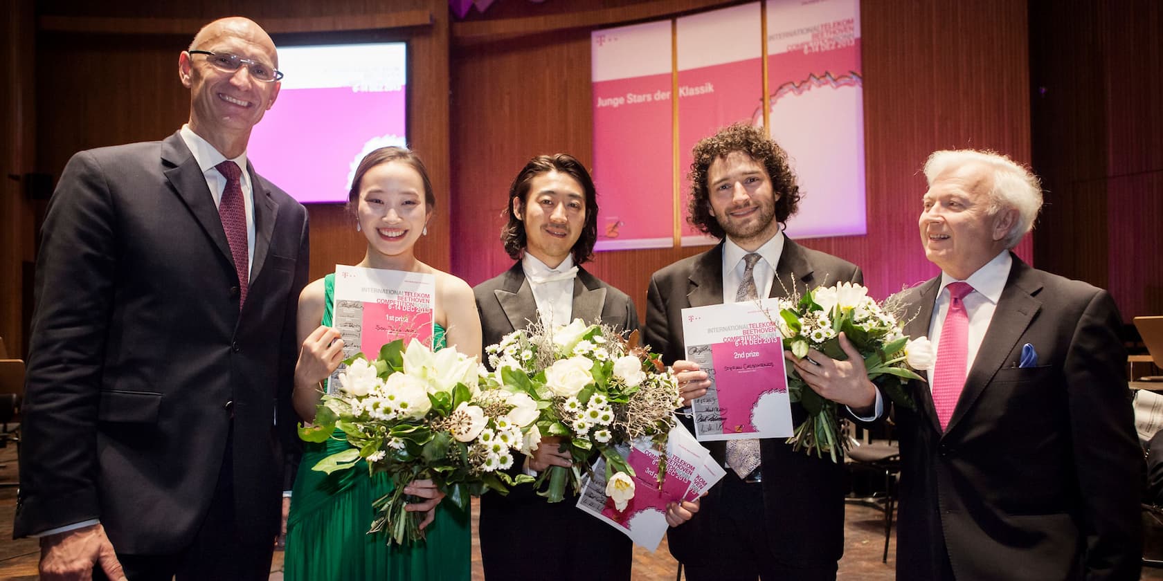 Gewinner des Internationalen Telekom Beethoven Wettbewerbs halten Urkunden und Blumensträuße bei der Preisverleihung.