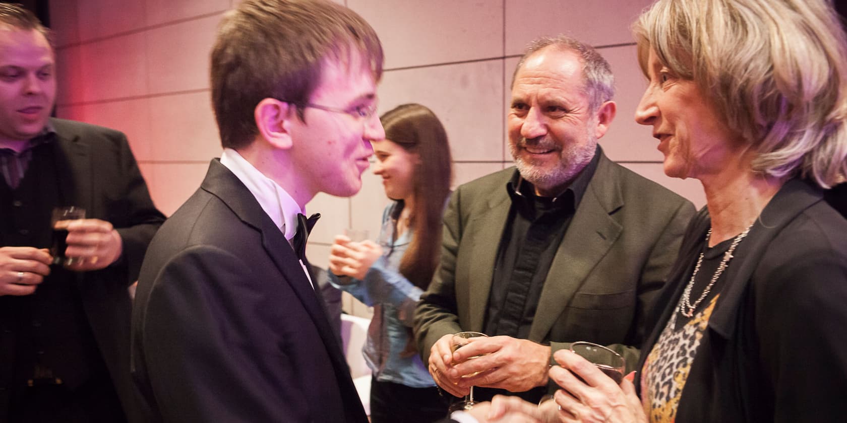 Several people in formal attire are conversing at an event.