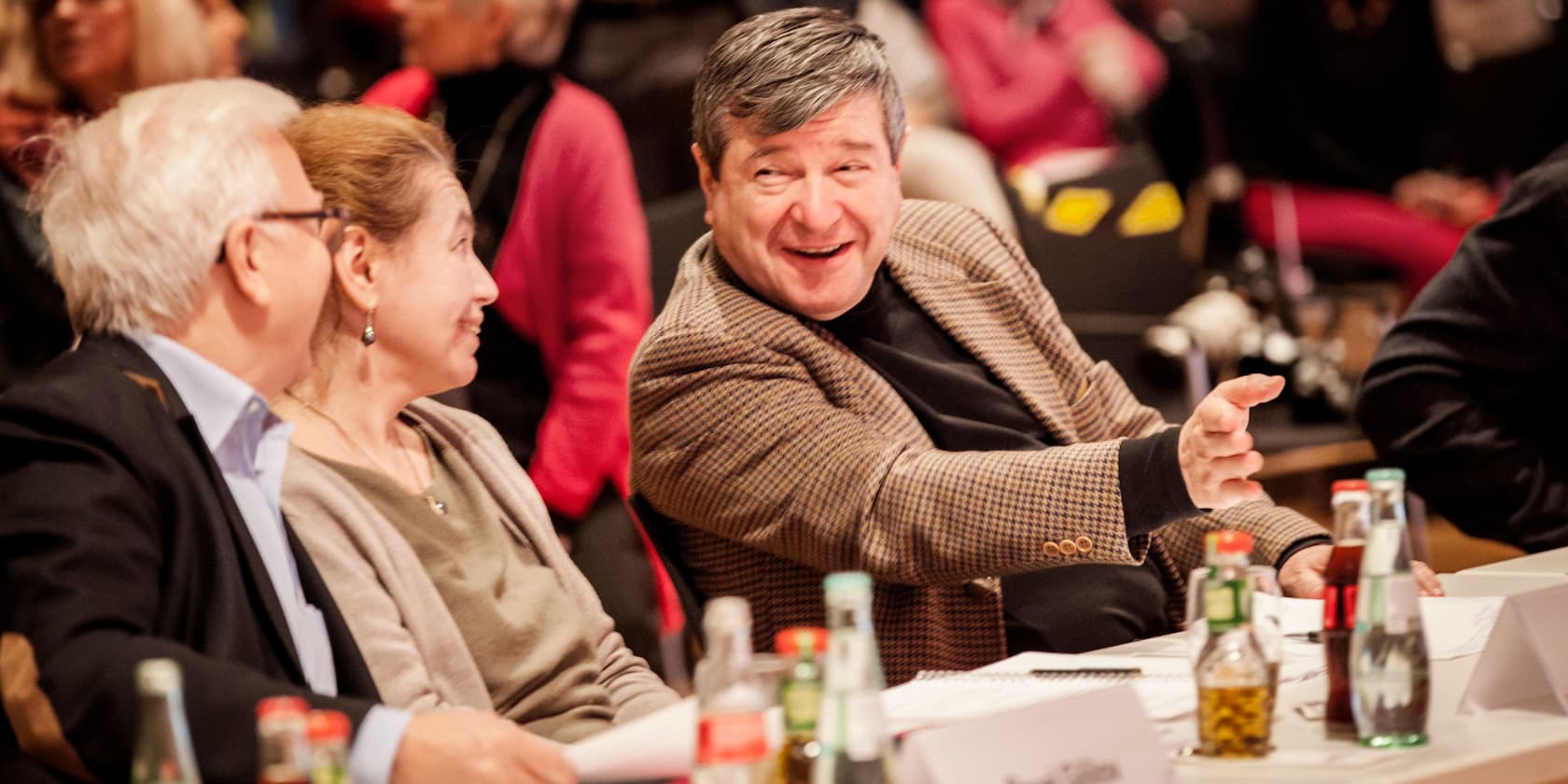 Three people sitting at a table having an animated conversation.