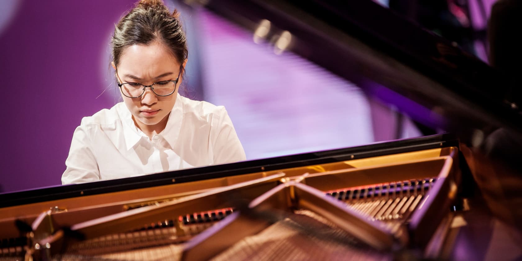 Woman with glasses playing the piano with concentration.