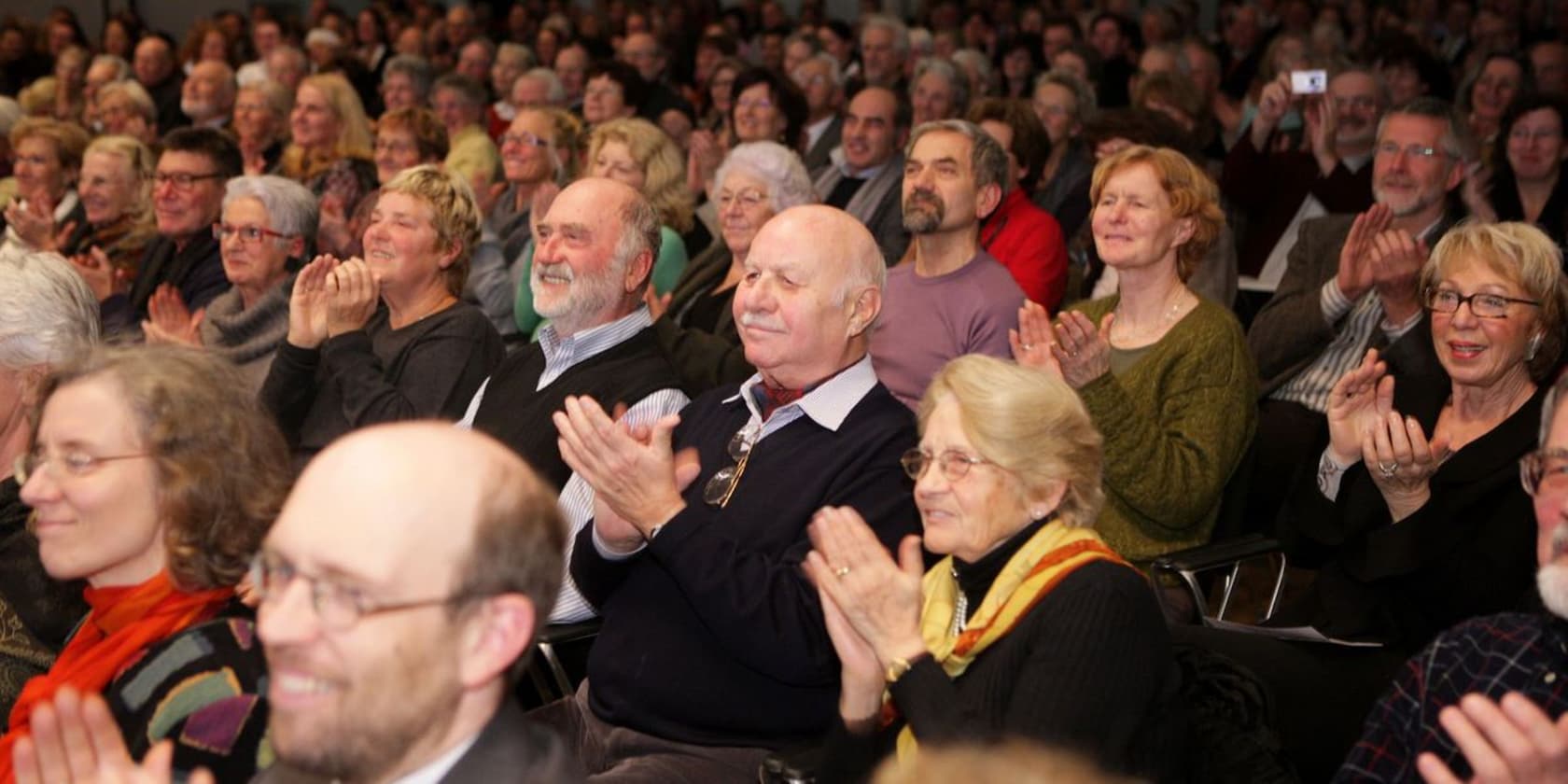 Eine Gruppe von Menschen applaudiert bei einer Veranstaltung.