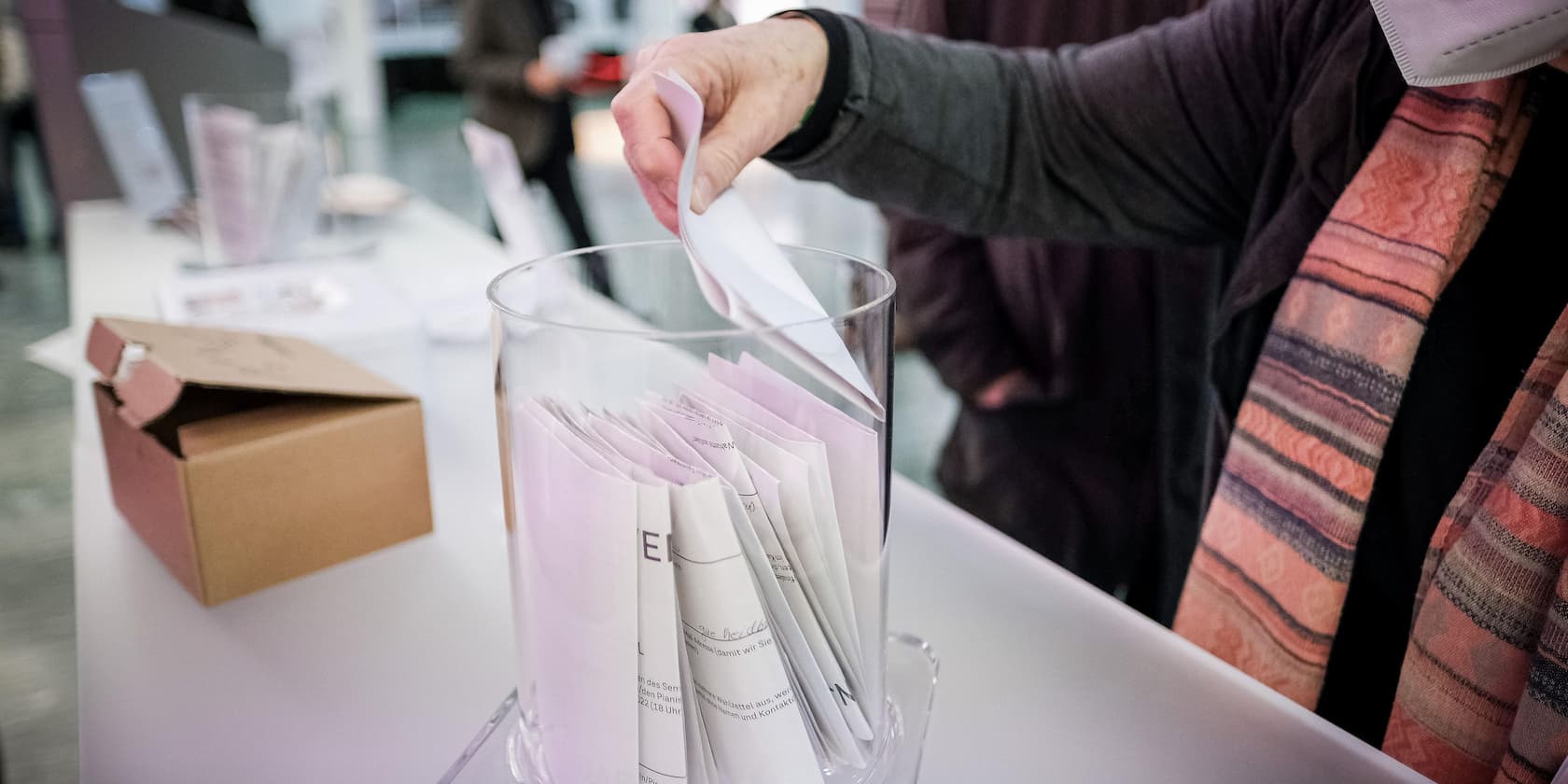 Hand dropping a paper into a glass box