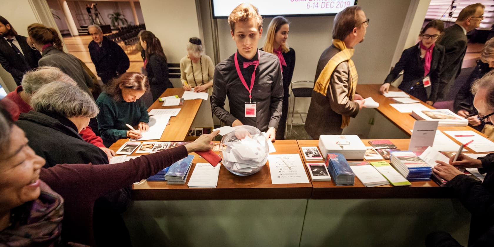 People are registering at a reception desk at an event.