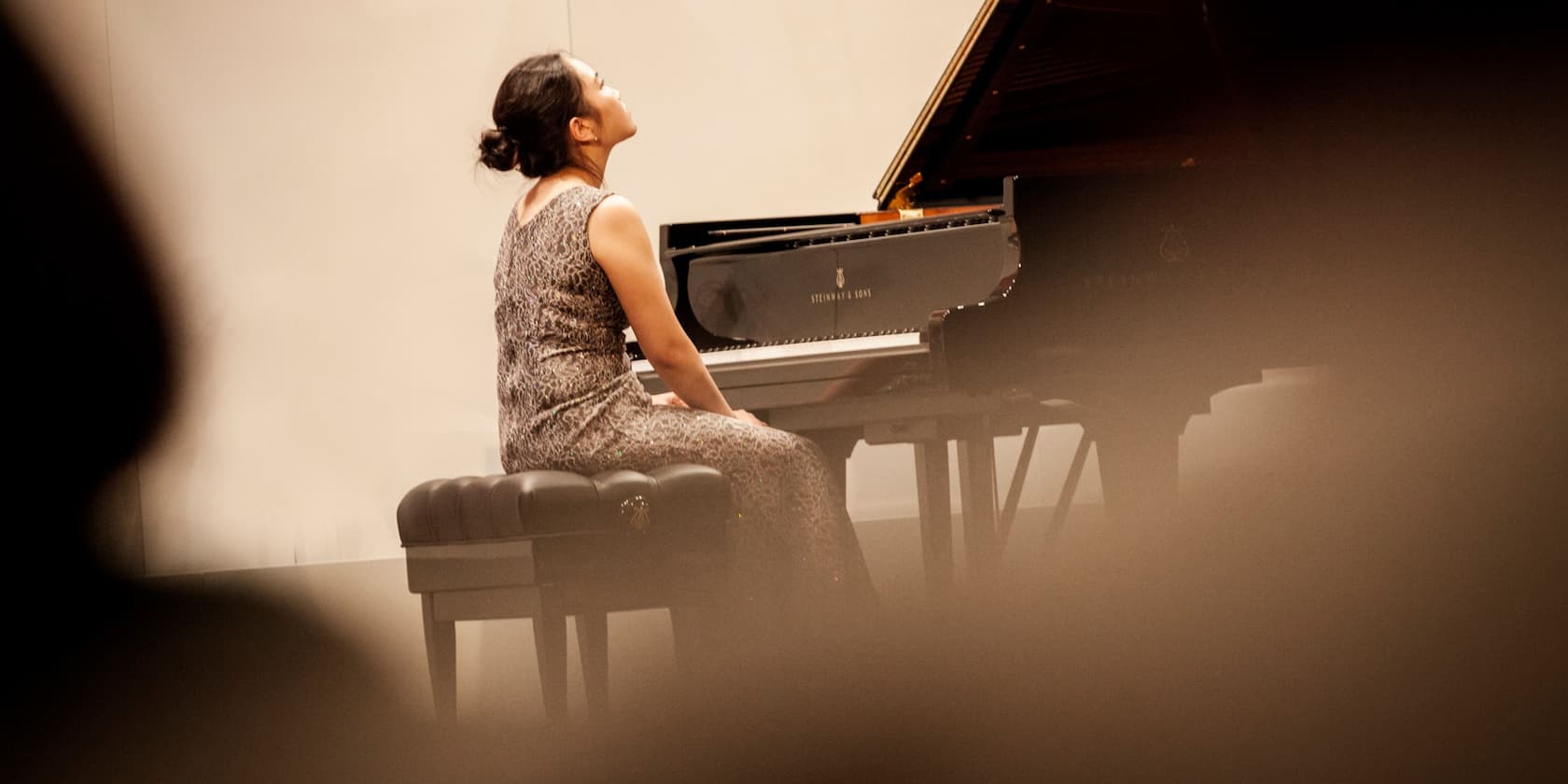 Woman sitting at a grand piano looking upwards