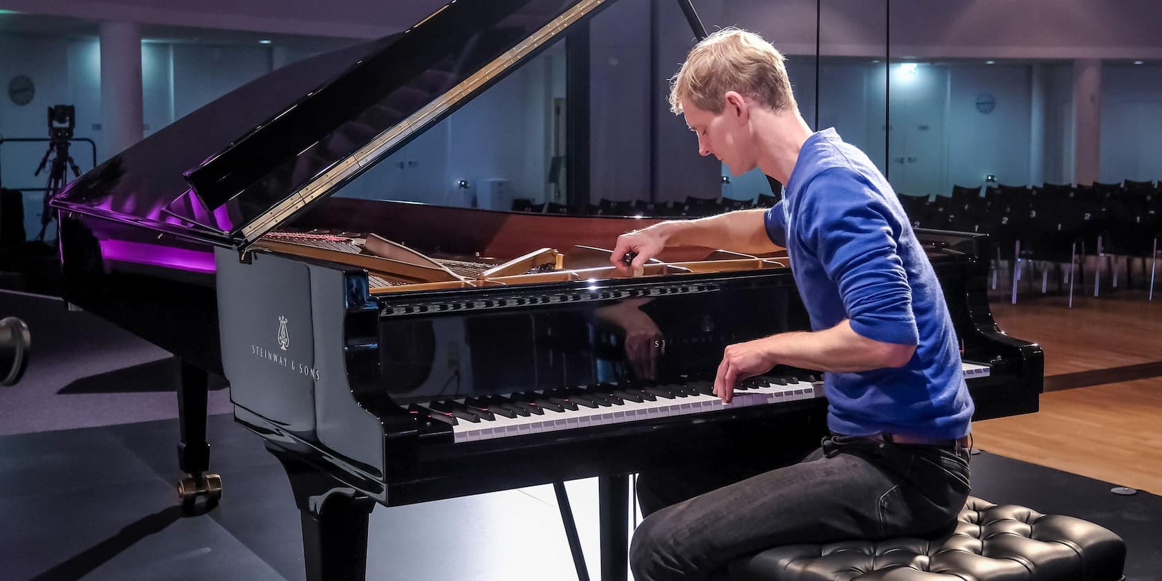 A man playing piano in an empty concert hall.