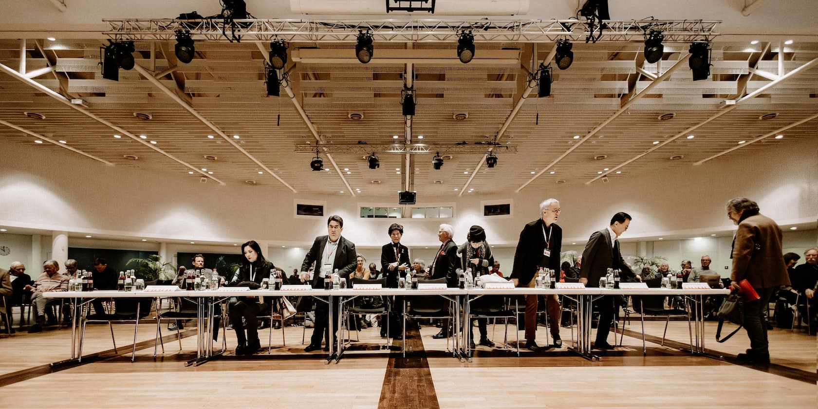 People preparing for a conference or event in a large, bright room with modern interior.