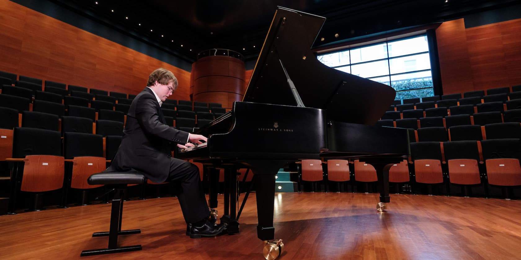 Person playing piano in an empty concert hall