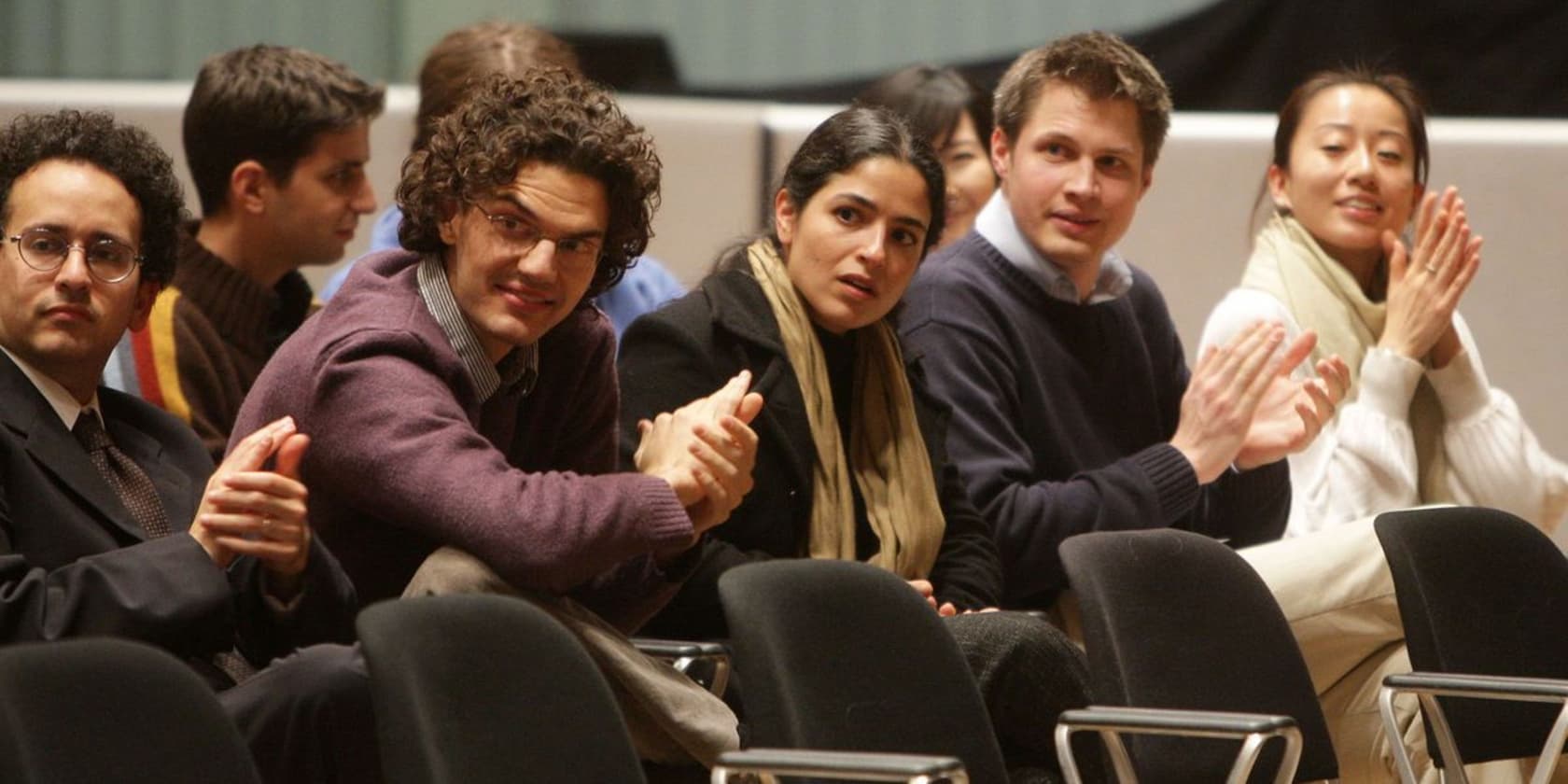 A group of people sitting and clapping at an event.