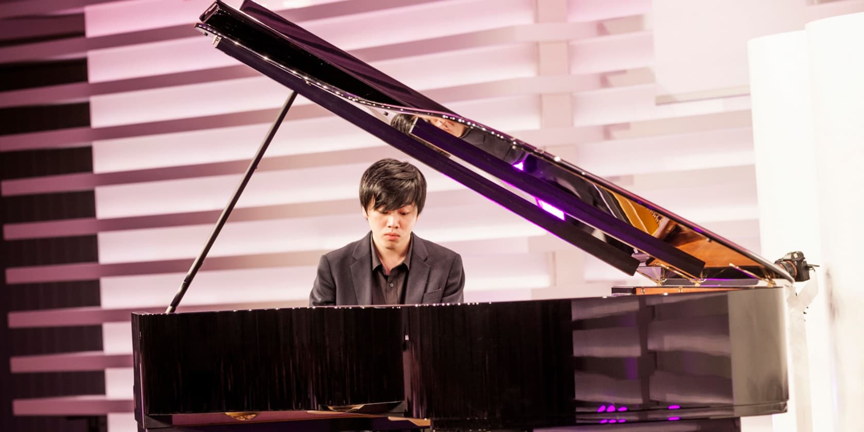 A man playing the piano in a modern, well-lit room.