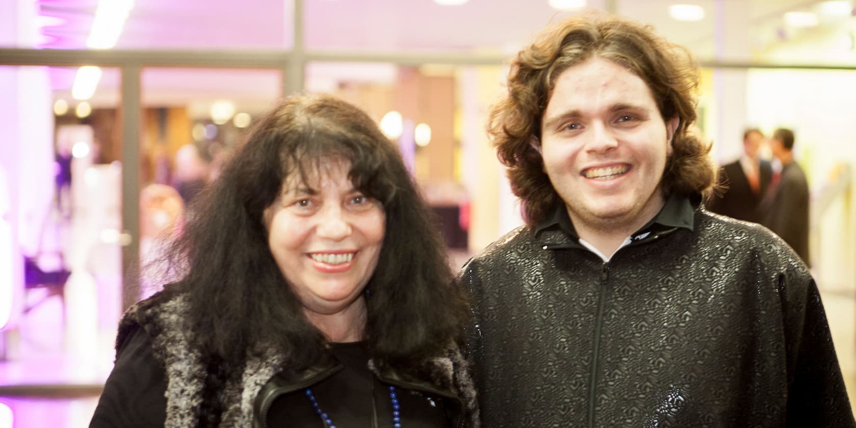 Two people smiling happily at the camera during an event.