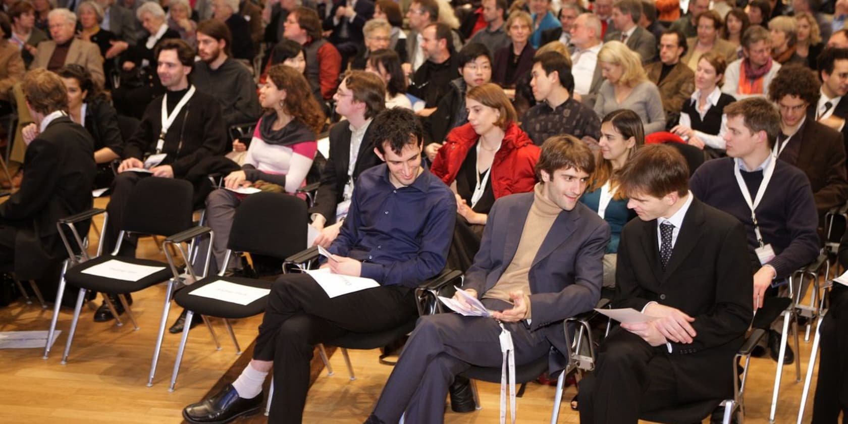 A crowd of people sitting on chairs, seemingly waiting for an event to begin.