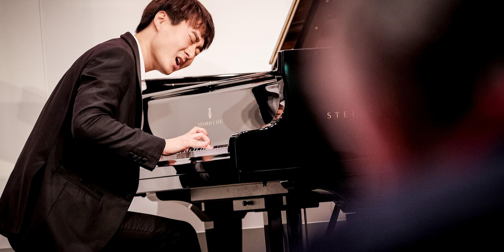 A musician playing intensely on a Steinway & Sons grand piano.