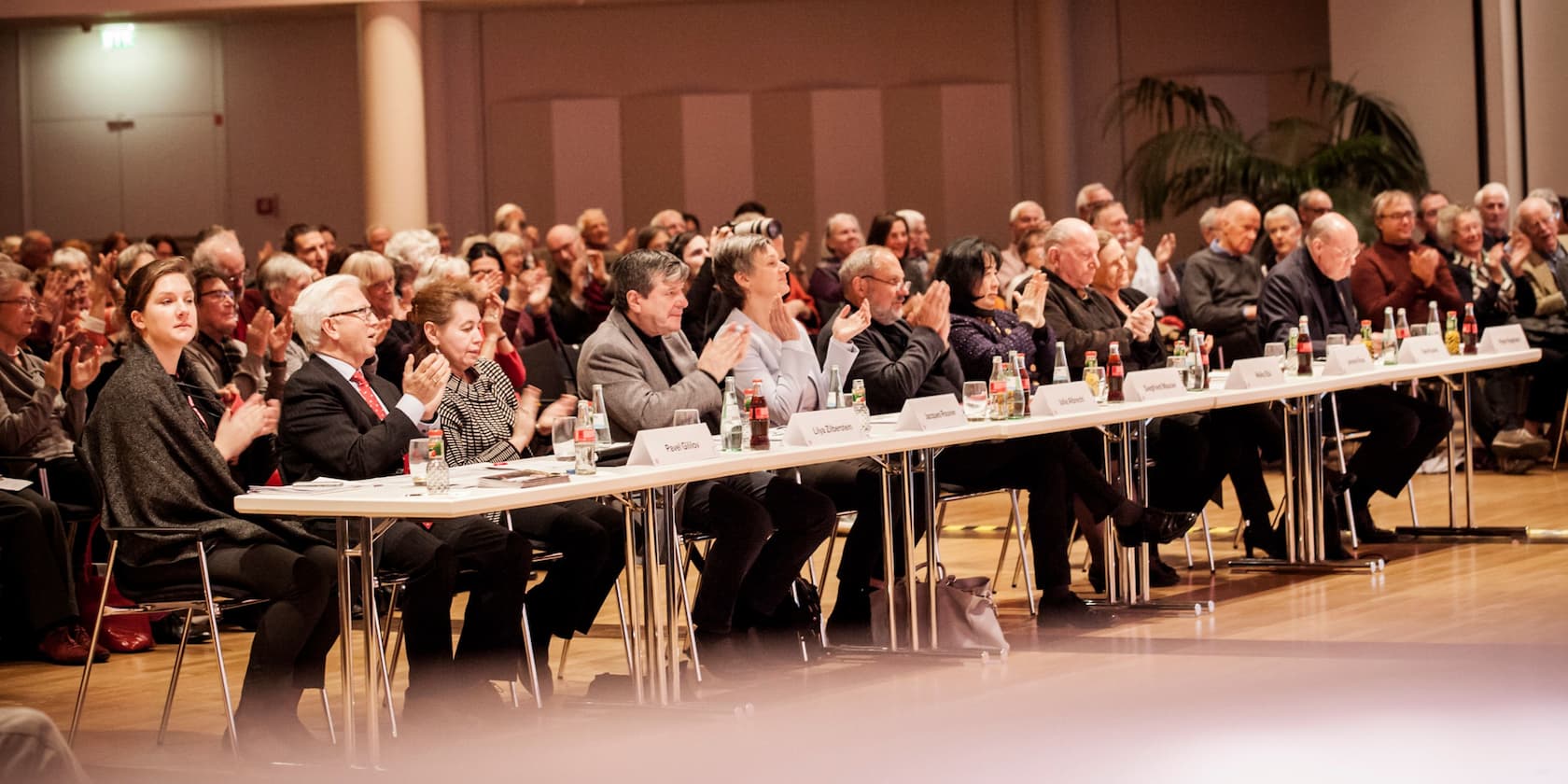 People in a conference room, some applauding.