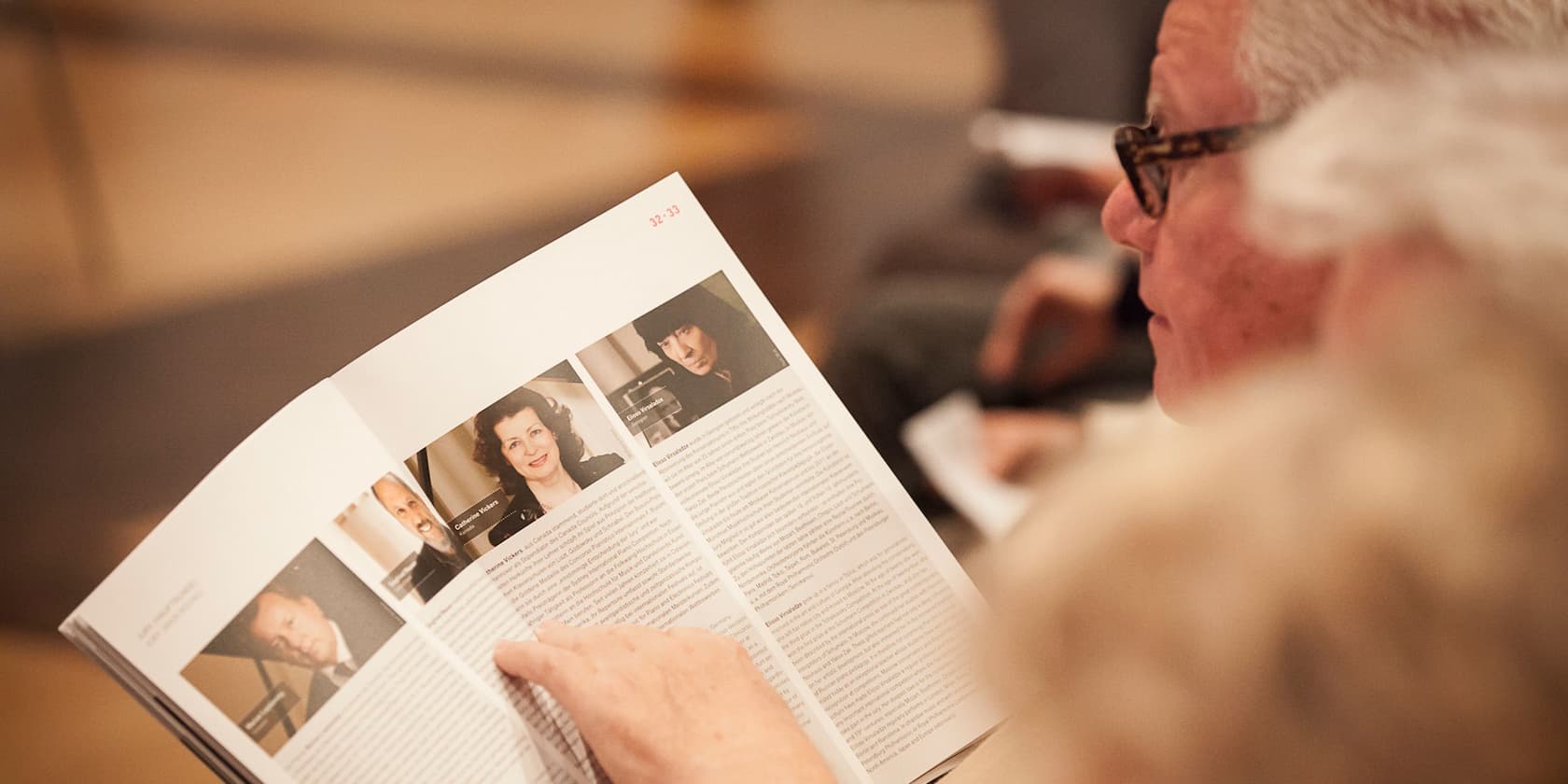 A person reading a brochure with articles and photos.