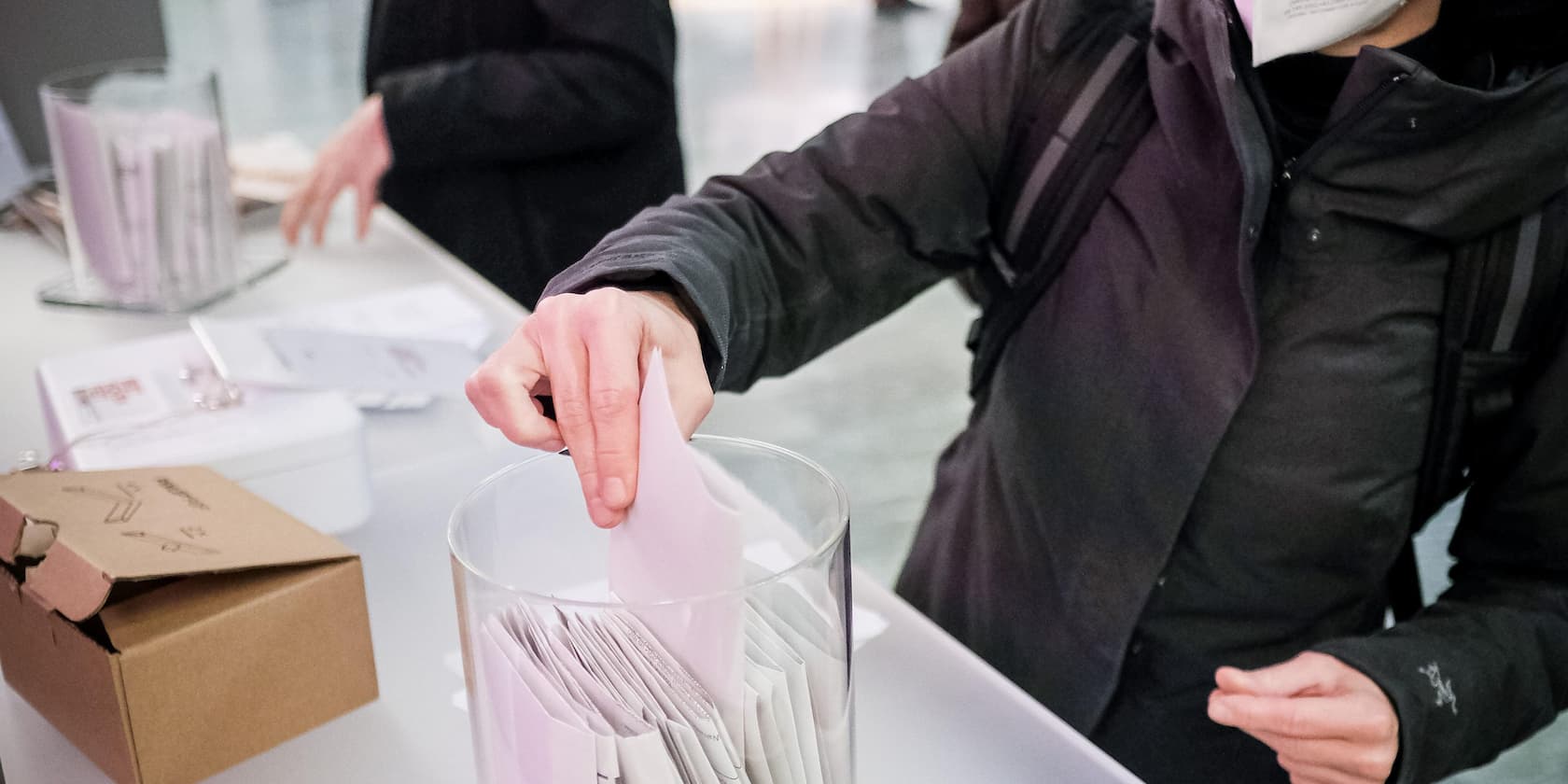 Person inserting a ballot into a voting box.