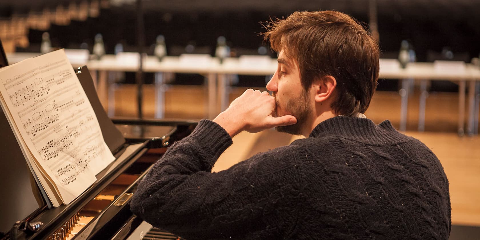 Man studying sheet music on a piano.