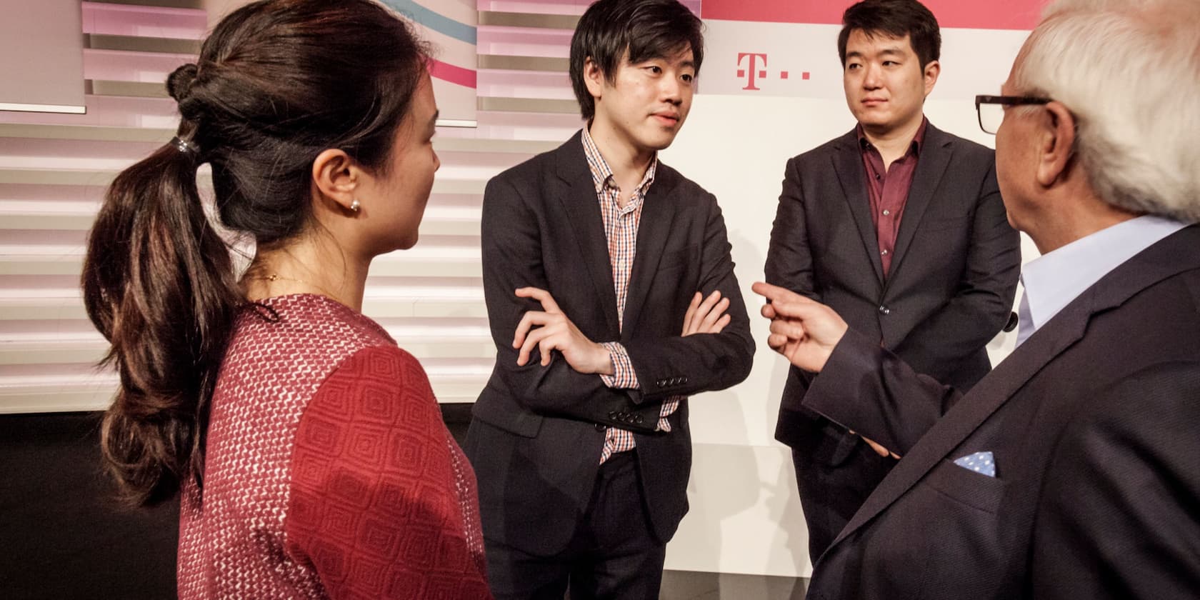 Four people in business attire having a conversation in a modern office.