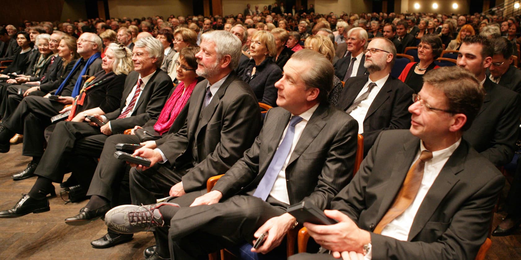 A large crowd of people seated in an auditorium, listening attentively.