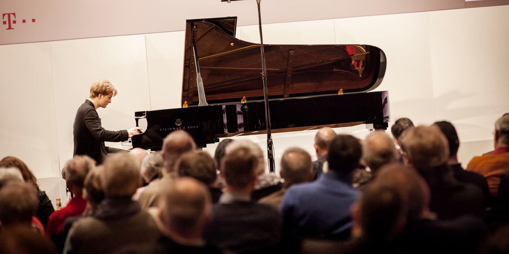 A pianist playing a grand piano in front of an audience.