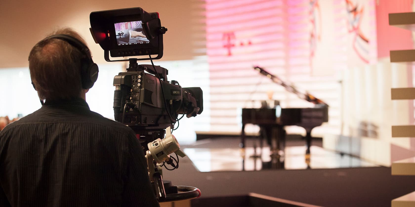 Cameraman filming a piano on stage.