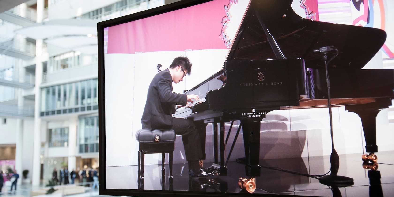 A pianist playing a grand piano in a modern building.