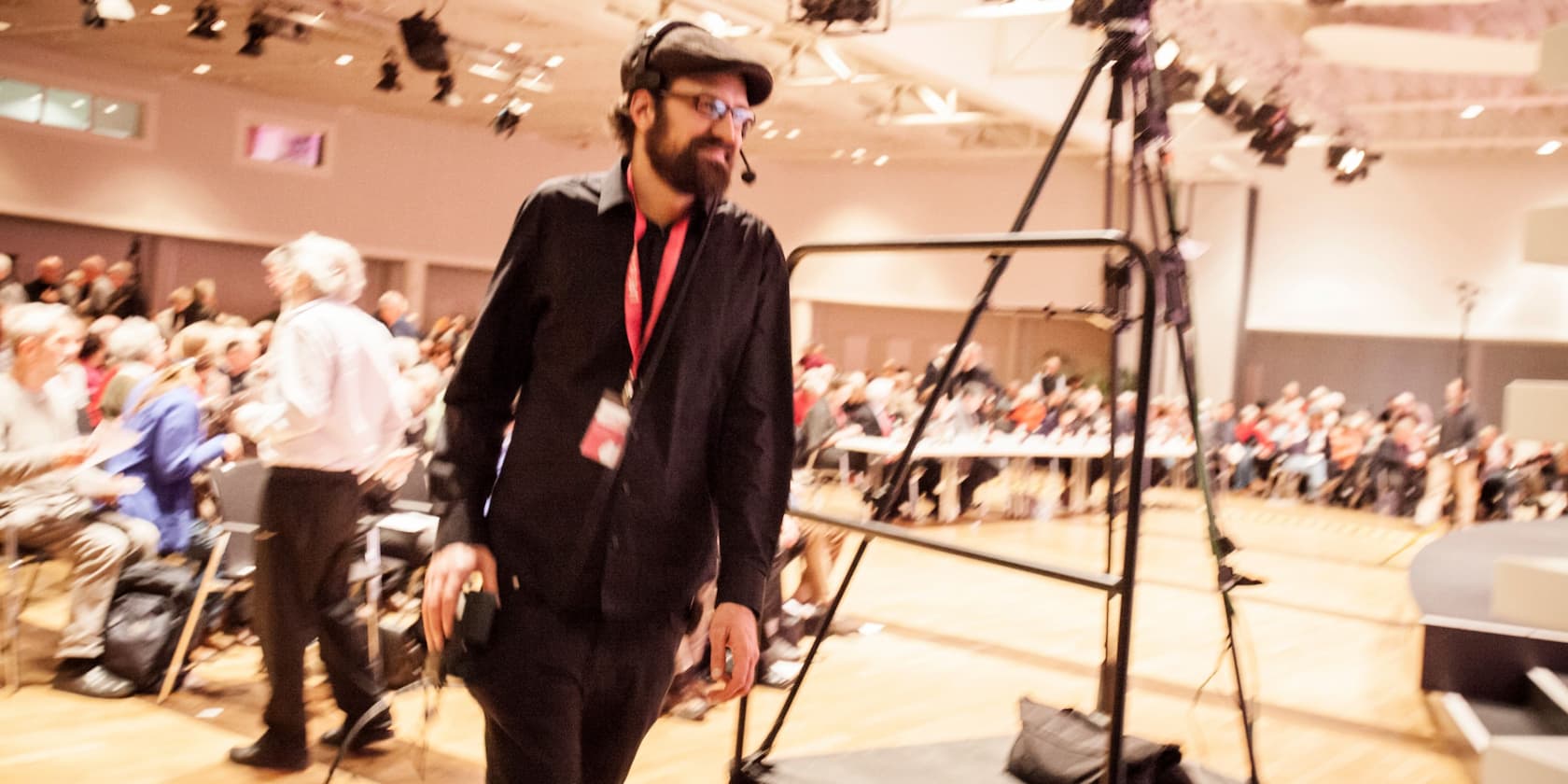 Technician with headset at an event, blurred crowd in the background.