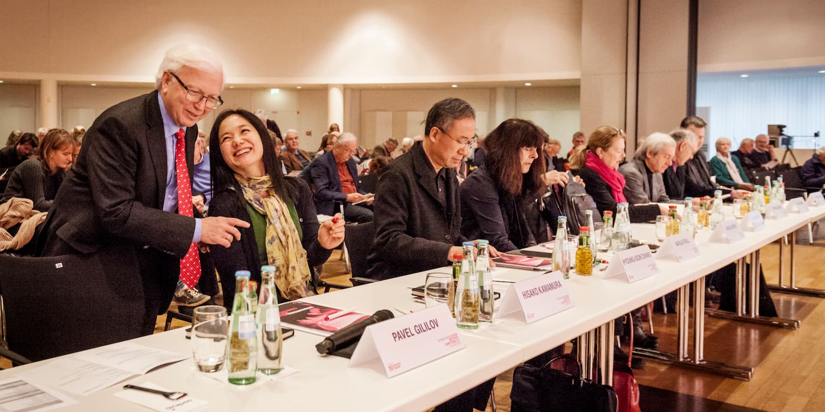 Participants at a conference sit at a long table and discuss.