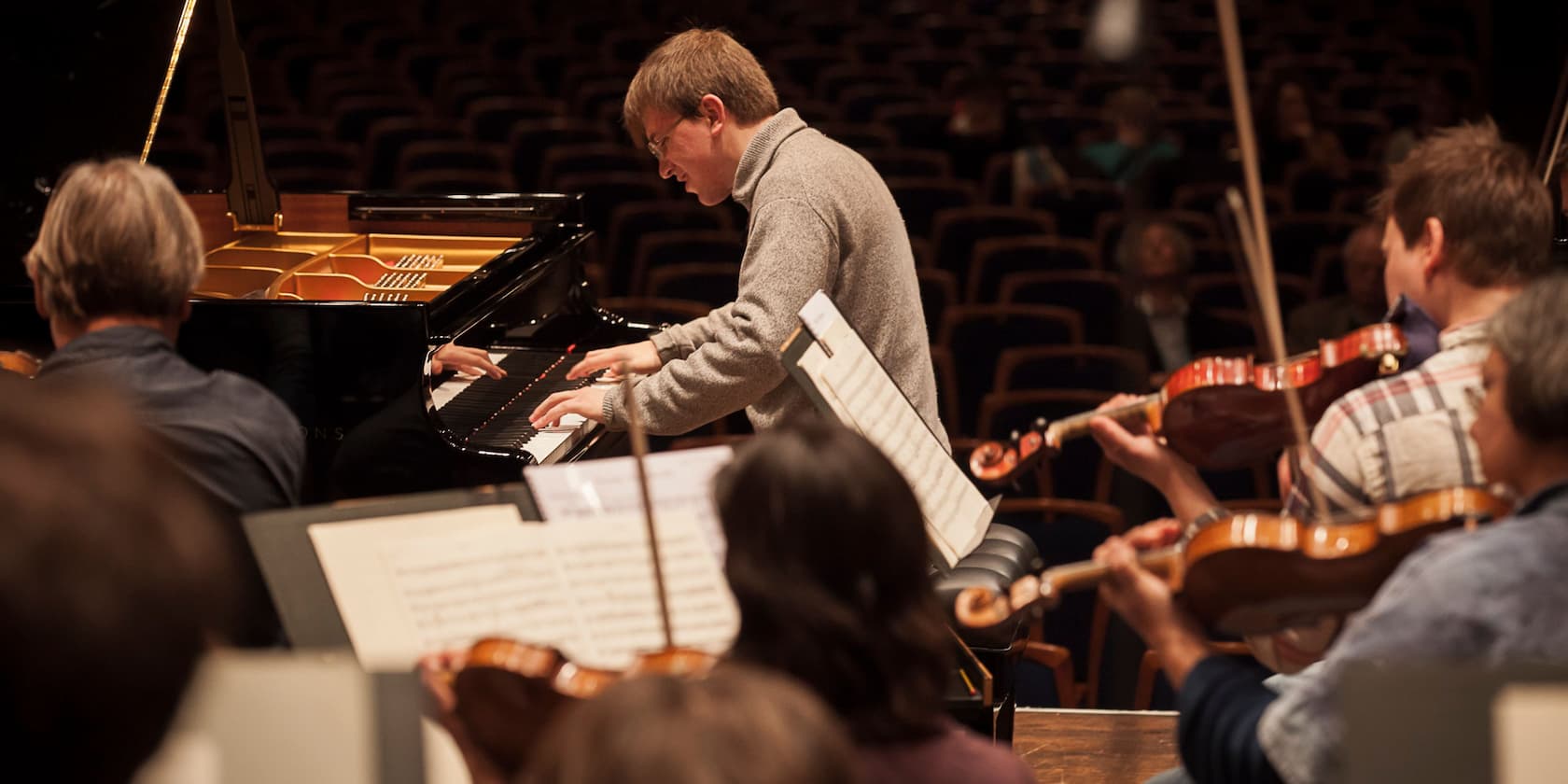 A man plays piano during an orchestra rehearsal.