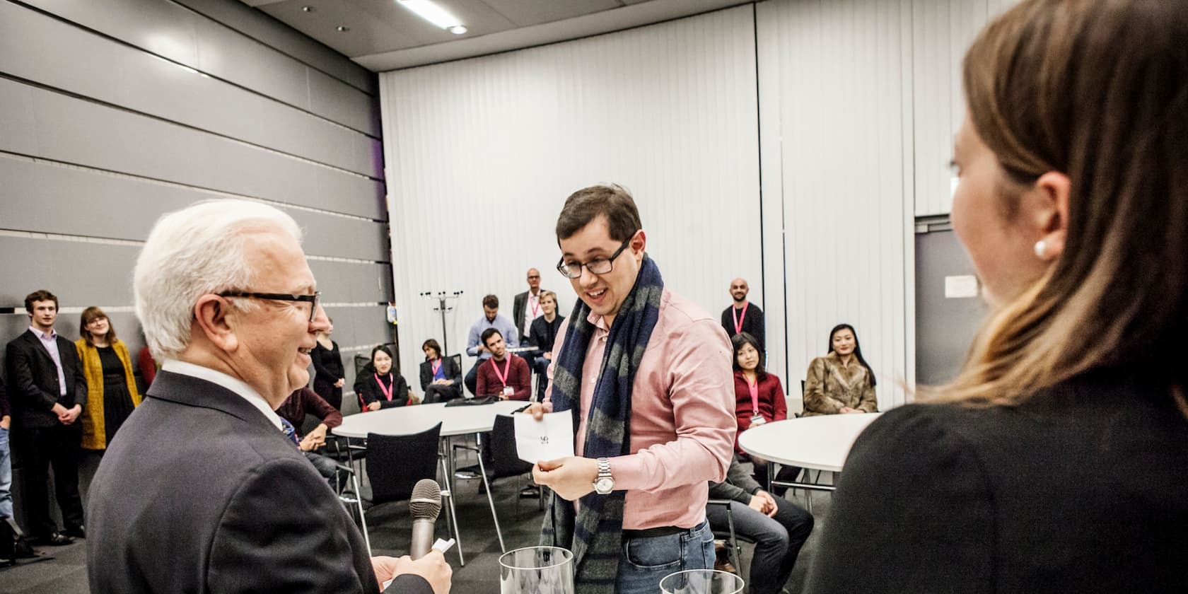 A person hands a card to another person while several people watch.