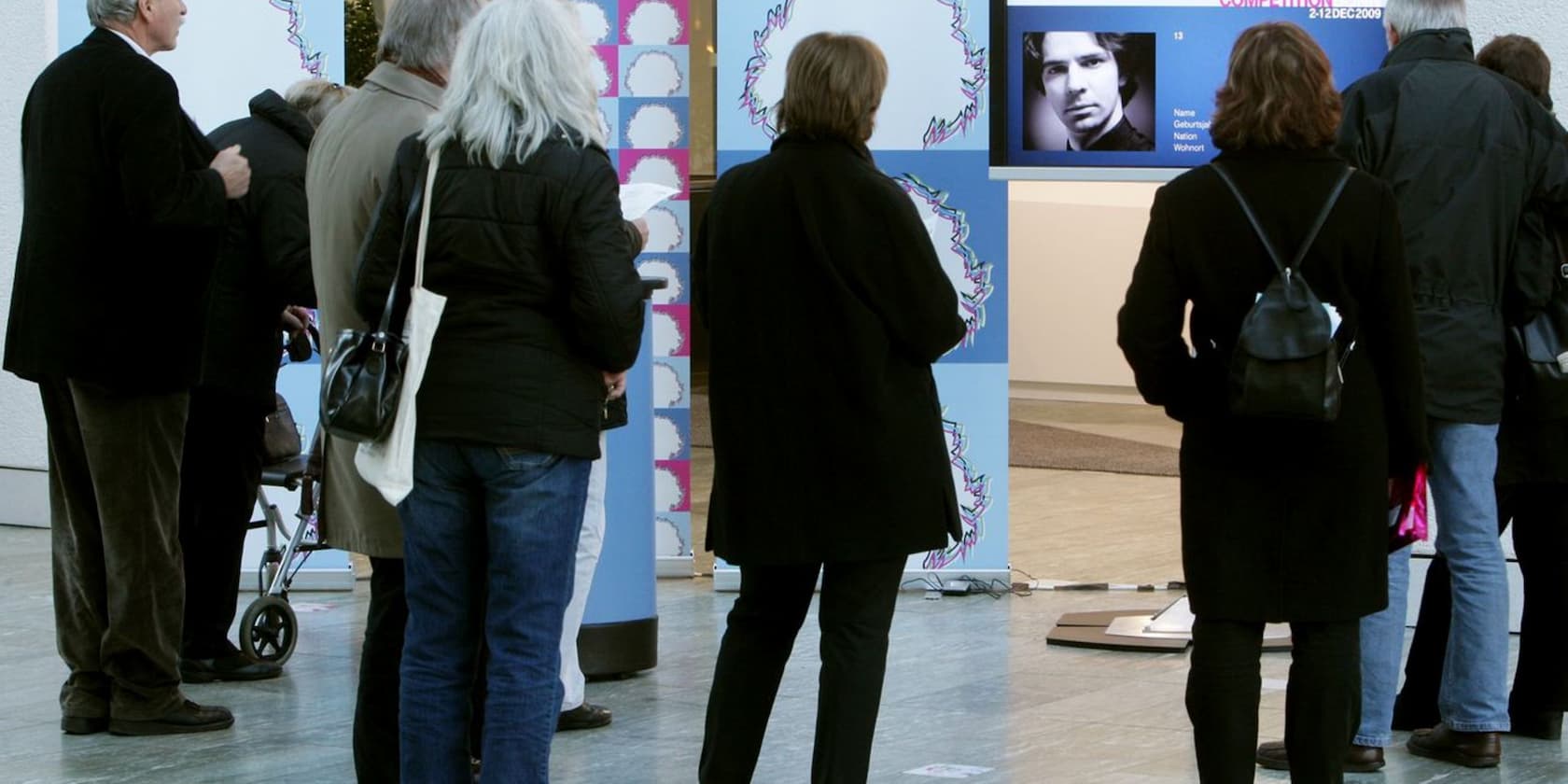 A group of people viewing a portrait photo exhibition.