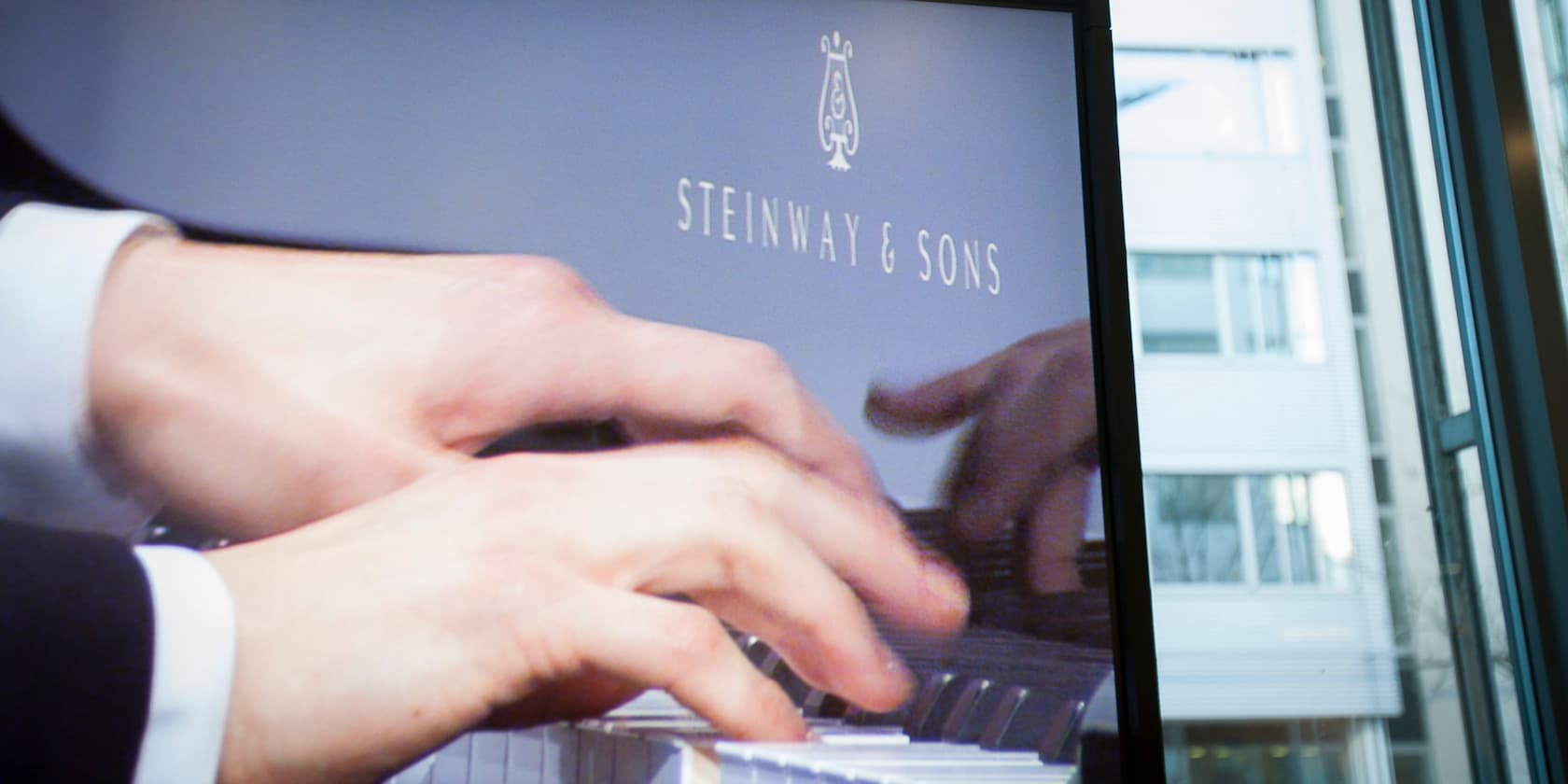 Hands playing piano with Steinway & Sons logo in the background