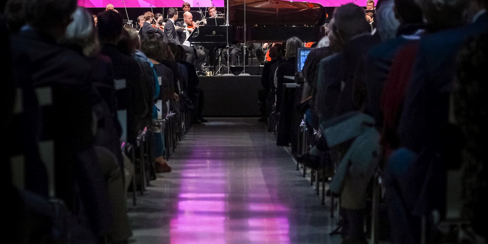 An orchestra performing in front of an audience in a concert hall.