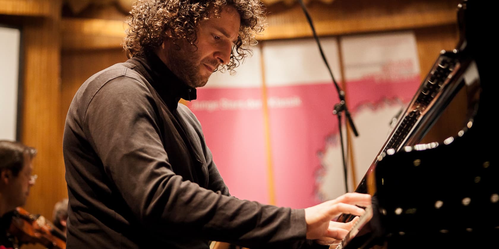 A man plays the piano intently during a concert.