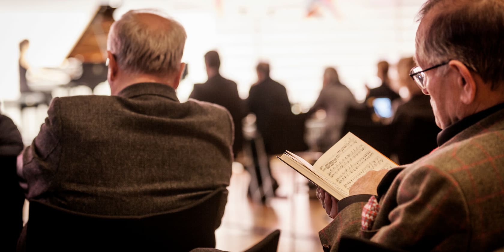 People at a concert, a person reading sheet music.