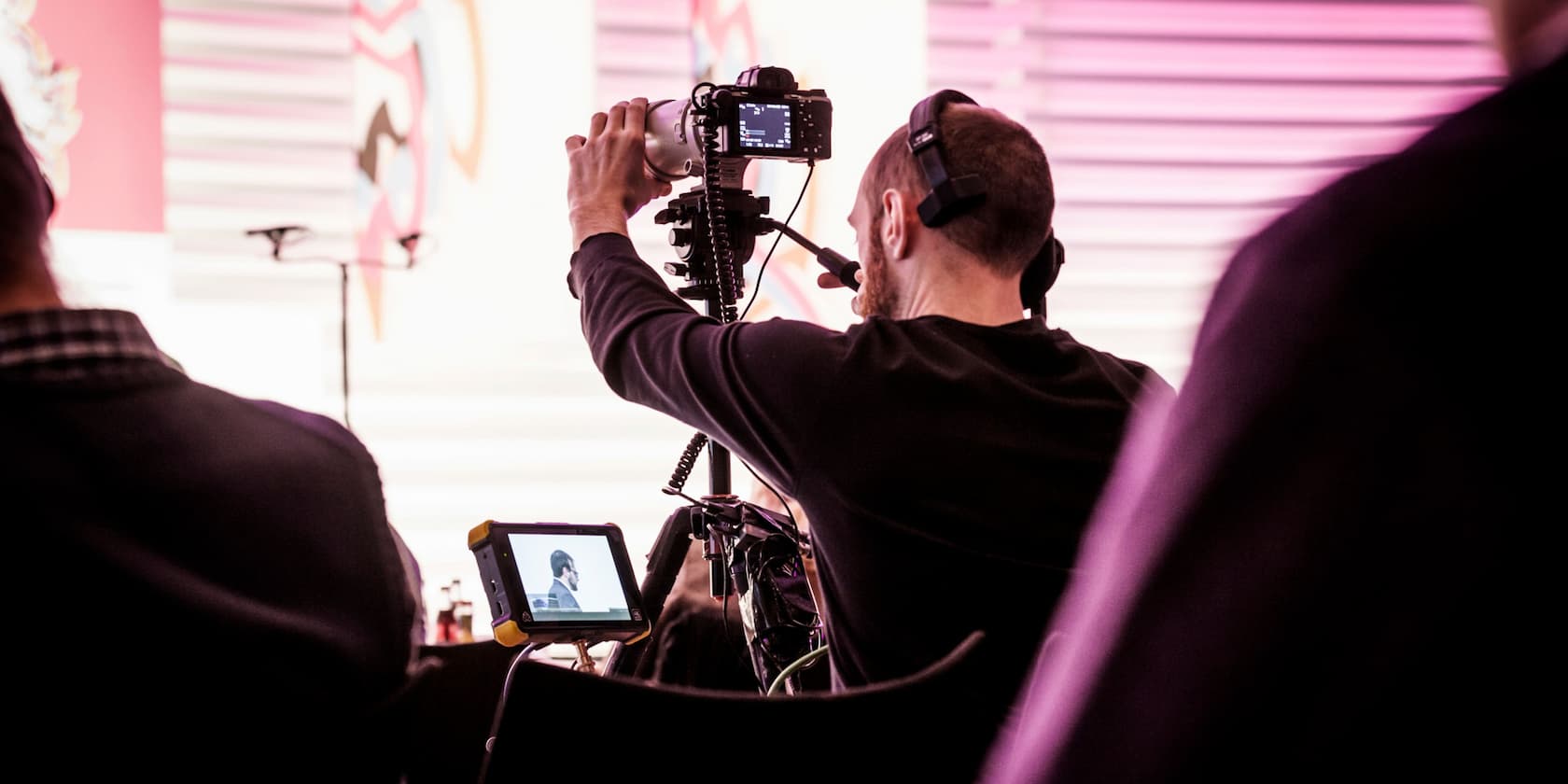 A cameraman filming a scene in a well-lit room.