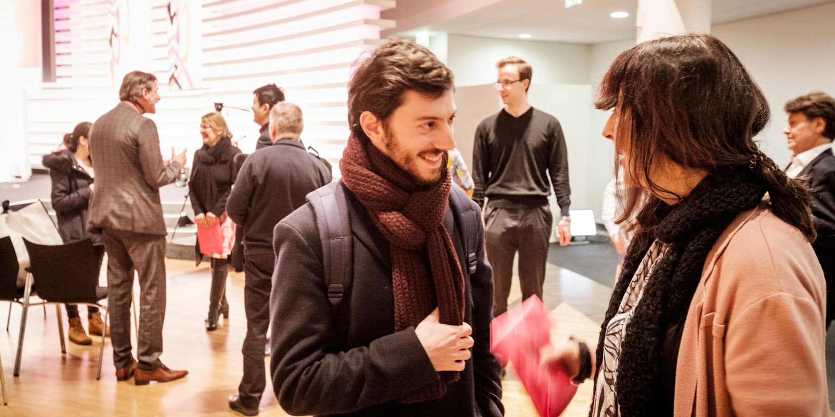 Personen unterhalten sich bei einem Meeting oder einer Veranstaltung in einem modernen Raum.