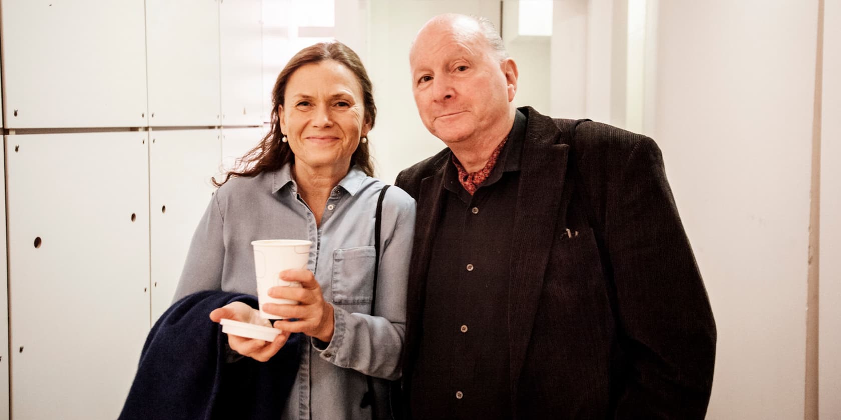 Woman with a cup and a man standing together and smiling.