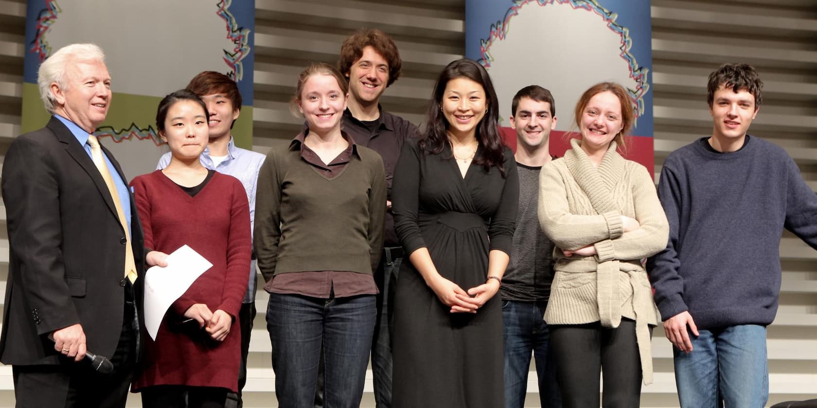 A group of eight people posing for a photo on a stage.