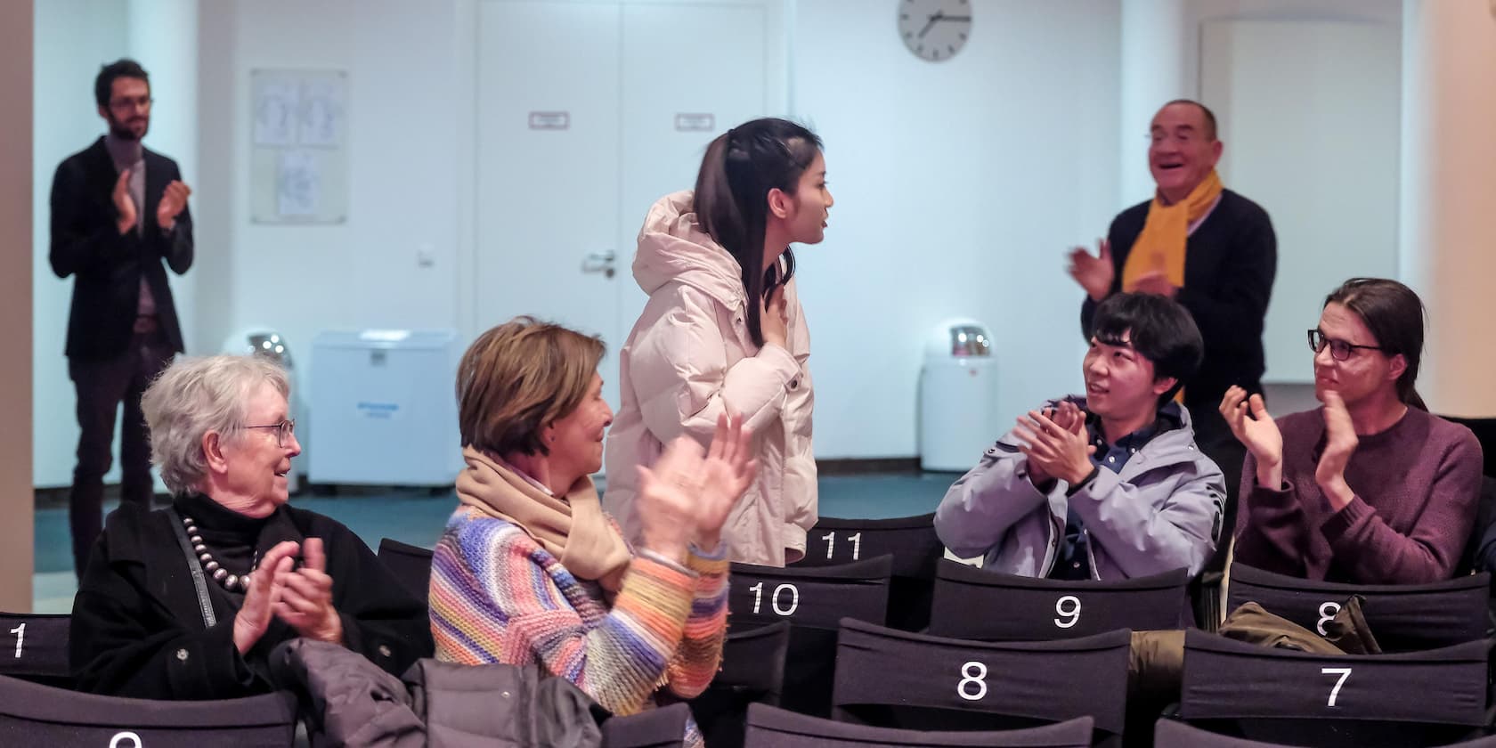 People in a room clapping for a woman who is standing up.