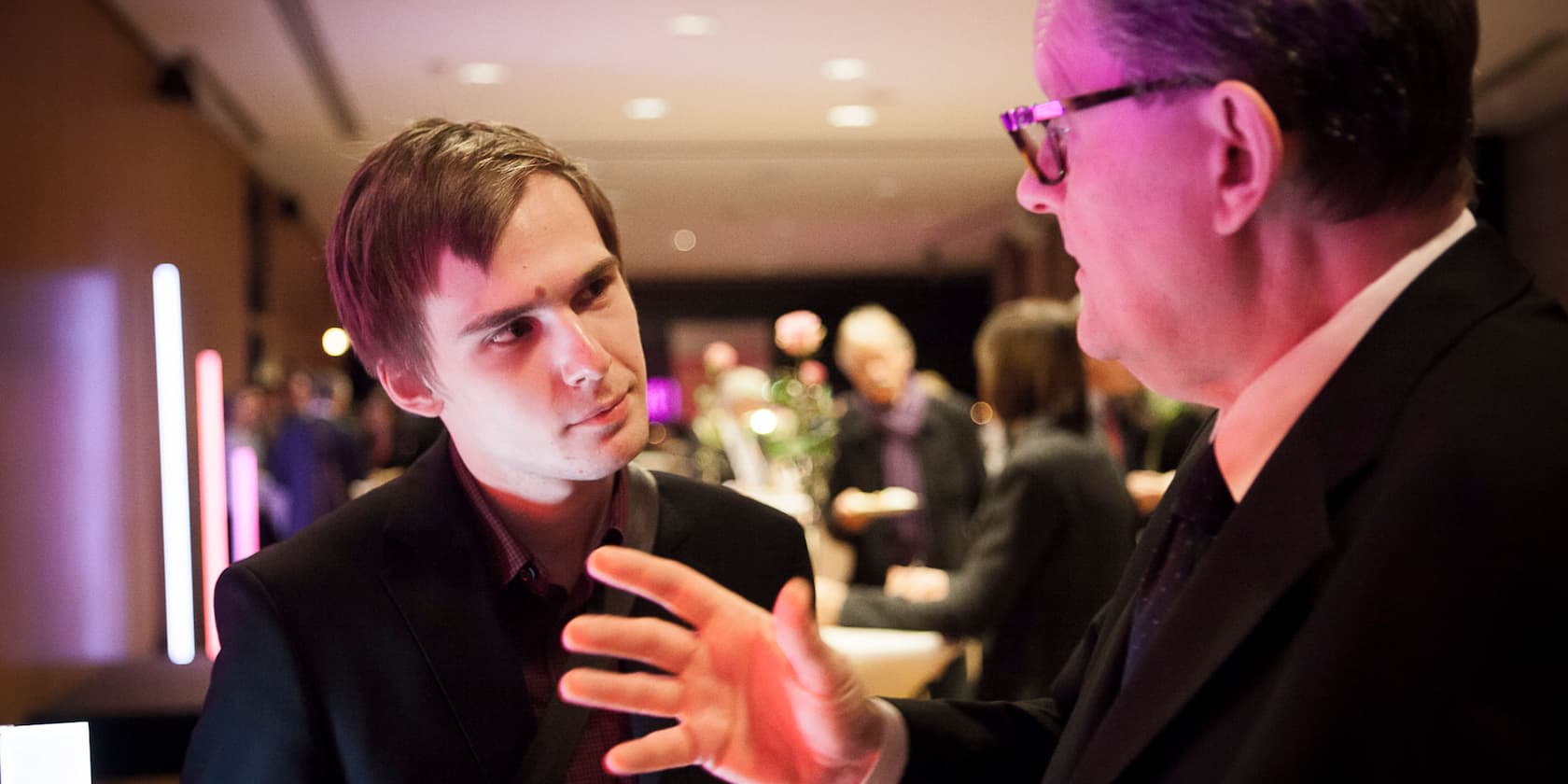 Two men in conversation at an event.