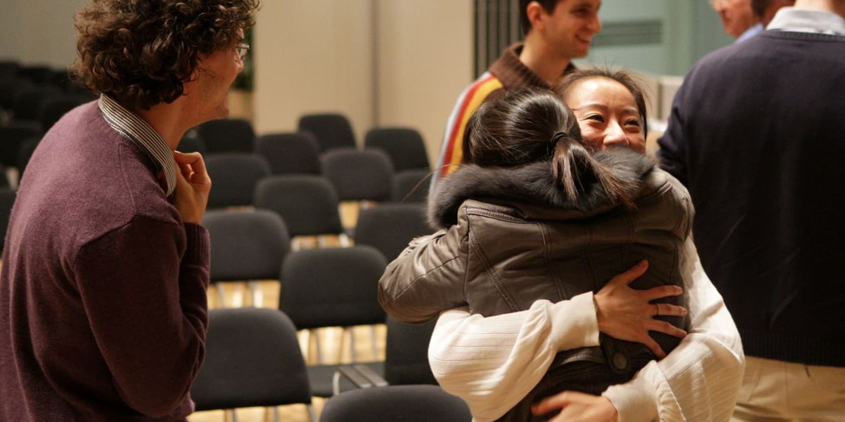 People hugging and smiling at a gathering.